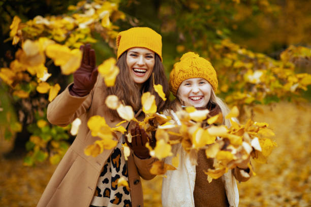 istock smiling modern mother and child throws up autumn leaves 1287448424