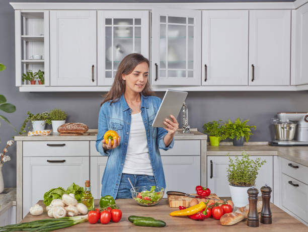 istock Woman with digital tablet cooking dinner 1287449253
