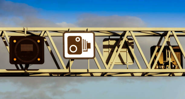 Close up view of an overhead gantry on a motorway. The sign shows traffic cameras are used to enforce speed limits.