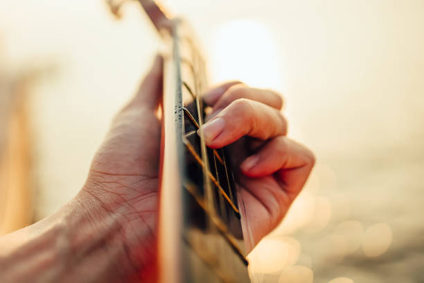 istock man playing guitar on sunset sea beach. 1287452321