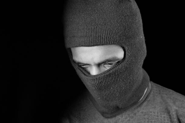 istock Thief in a mask on black background close up, 1287453328