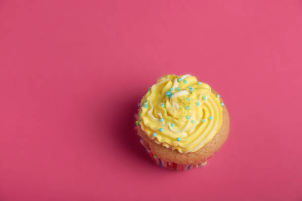 istock cupcake with yellow cream on a pink background. 1287453675