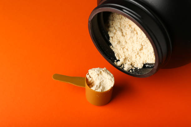 istock protein powder on orange background top view with copy space. 1287454979