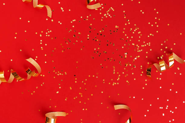 istock Golden swirls and star shaped sparkles on red 1287455143