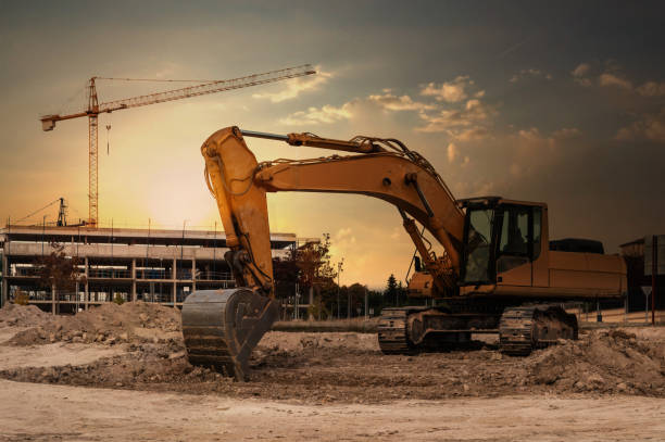 A large excavator at a construction site with cranes and scaffolding in the background