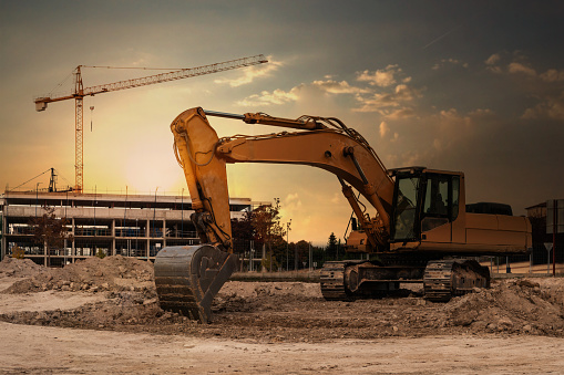 A Large Excavator At A Construction Site With Cranes And Scaffolding In The  Background Stock Photo - Download Image Now - iStock