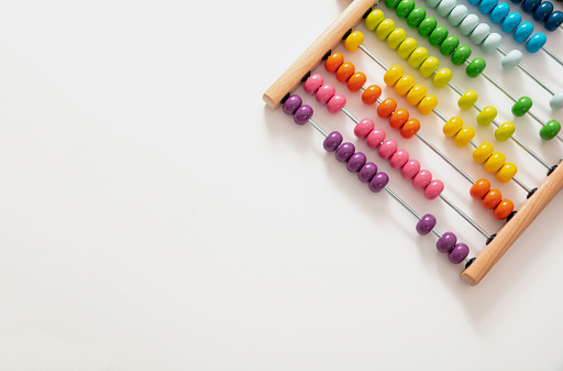 School abacus with colorful beads on white color background, close up view, copy space. Kids learning count, children math class concept