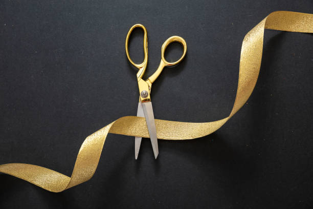 grand opening. gold scissors cutting gold satin ribbon, black background - beginnings business new business ribbon imagens e fotografias de stock