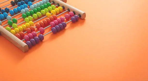 Photo of School abacus with colorful beads on orange color background, close up view