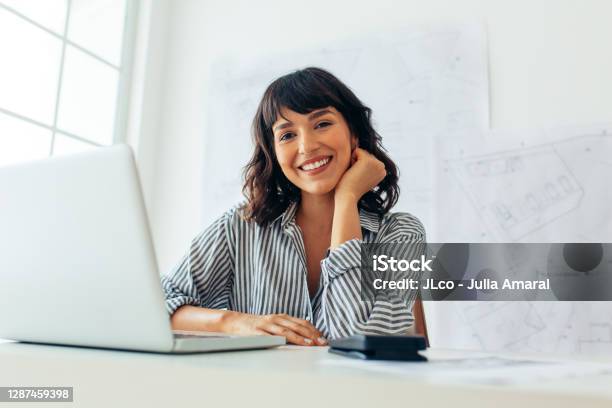 微笑的女建築師坐在她的辦公桌上 照片檔及更多 僅一名女人 照片 - 僅一名女人, 幸福, 人