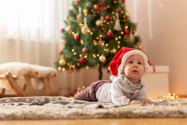 istock Baby boy wearing Santa hat lying by the Christmas tree 1287463546