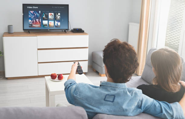istock Young couple watching TV on sofa 1287464044