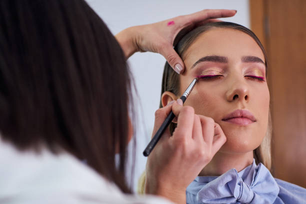 istock Precise makeup artist using a thin eye liner brush to apply a purple eyeliner for complete make up look 1287464218