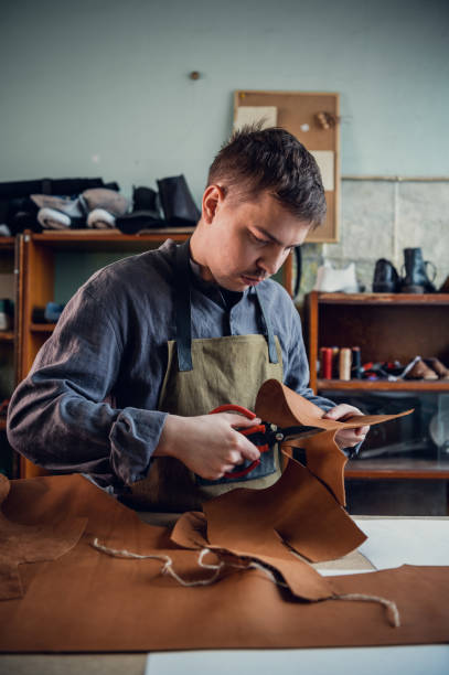 istock A young tanner in his workshop at the table cuts out leather elements of shoes 1287464341