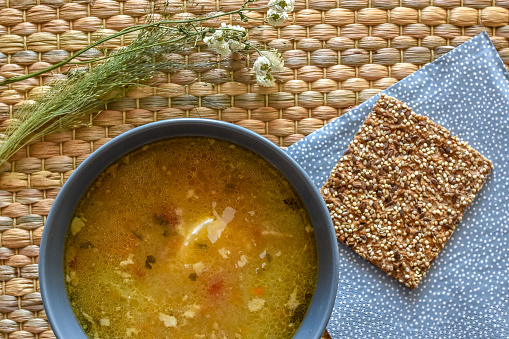 Fresh made chicken soup with bread on the rustic background