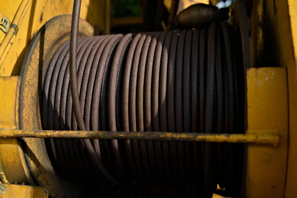 Dirty steel cable winch on and excavator. Close up.