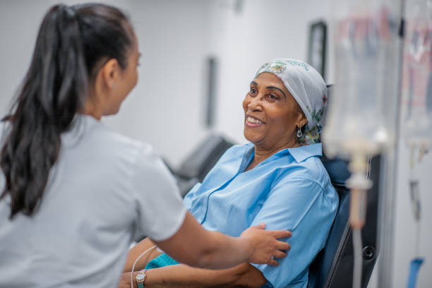 Giving emotional support to a cancer patient A nurse visits her patient at her hospital chair and the patient smiles. chemotherapy drug stock pictures, royalty-free photos & images