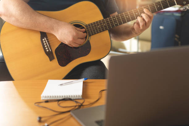 istock Man learns to play the guitar using online video lessons. 1287467299
