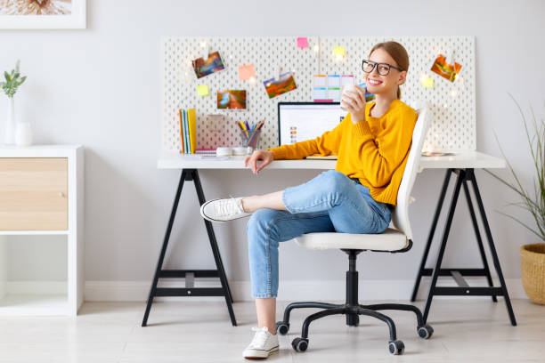 Delighted woman drinking coffee during work at home