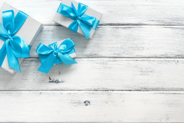 istock Gift boxes with blue bow on a white old wooden background. Top view, flat lay. Holiday and shopping concept. 1287469632