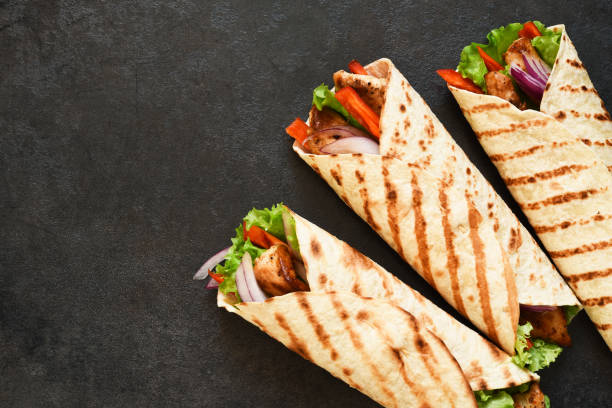 istock Mexican tortilla grilled wrap with chicken breast and vegetables on concrete background 1287470814