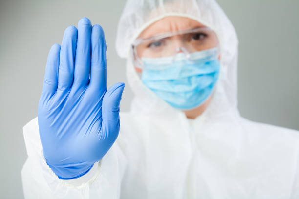 istock Lab scientist doctor wearing biohazard protective suit hand gesturing STOP Coronavirus 1287471119