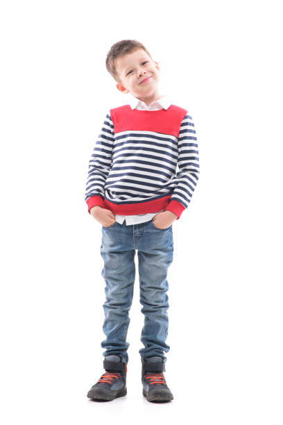 istock Cute smiling young well-dressed kid in jeans and sweater posing and looking at camera. 1287472209