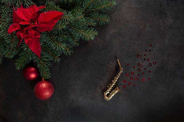 ミニチュア金色のサックスコピー、クリスマスツリーの枝とポインセチア。 クリスマスと新年のコンセプト。トップビュー、クローズアップ - ragtime ストックフォトと画像