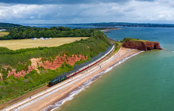Steam train at Dawlish A lovely drone image showcasing a steam train leading the way along the famous Dawlish Sea Wall. devon photos stock pictures, royalty-free photos & images
