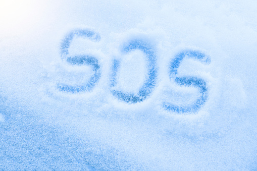 Text SOS written on a snow