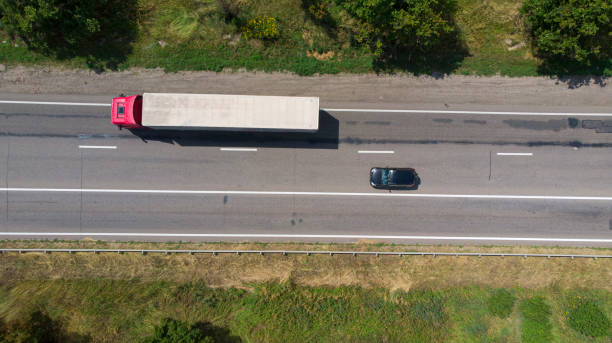 Aerial. Commercial truck driving by the highway. Black car going to overtake. Top view from drone. Aerial. Commercial truck driving by the highway. Black car going to overtake. Top view from drone. car transporter photos stock pictures, royalty-free photos & images