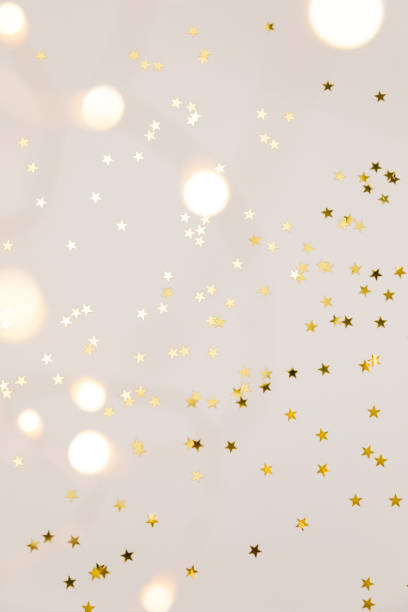 Festive gold background. Shining stars confetti and fairy lights on beige and Set Sail Champagne background. Christmas. Wedding. Birthday. Flat lay, top view, copy space stock photo