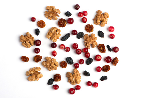Dried cranberries, walnuts, raisins, on white paper background. Close up.