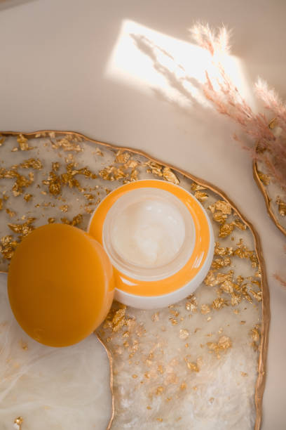 weiße kosmetik creme glas mit orangen deckel auf pastell - faltenreduktion fotos stock-fotos und bilder