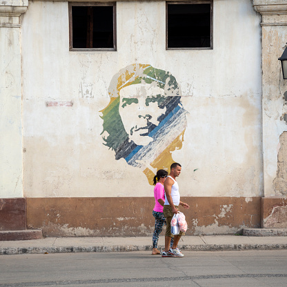 Havana, Cuba - December 16, 2014: Two people in the old town of Havana walk past a mural of Ernesto 