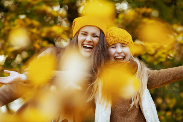 istock happy modern mother and daughter throws up autumn leaves 1287480982