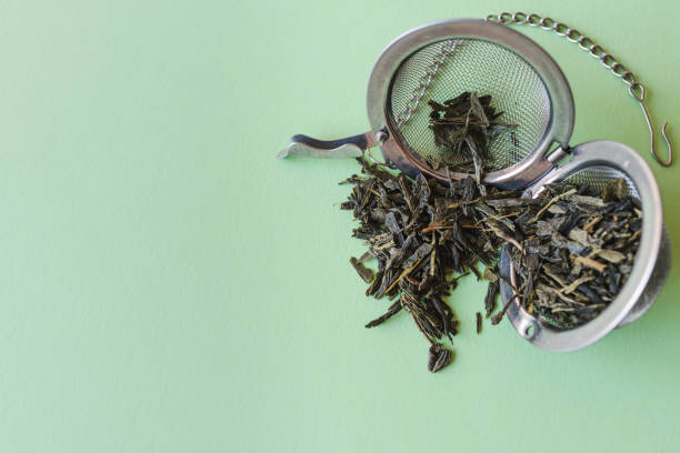 filtro de chá e folhas de chá verde no topo de uma mesa verde claro - dry dried plant green tea antioxidant - fotografias e filmes do acervo
