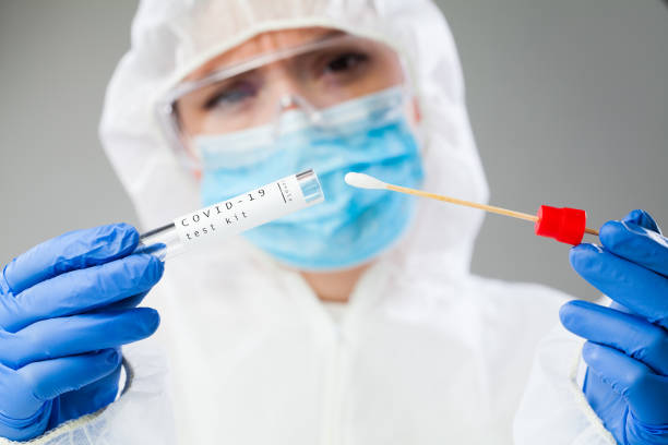 Coronavirus medical worker Medical healthcare technologist holding COVID-19 swab collection kit, wearing white PPE protective suit mask gloves, test tube for taking OP NP patient specimen sample,PCR DNA testing protocol process pcr device stock pictures, royalty-free photos & images