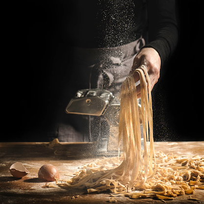 Hand holding fresh pasta, low light, flour dust