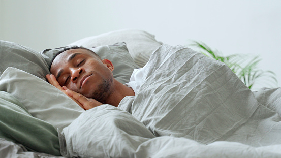 Young african-american man sleeping in bed at home.