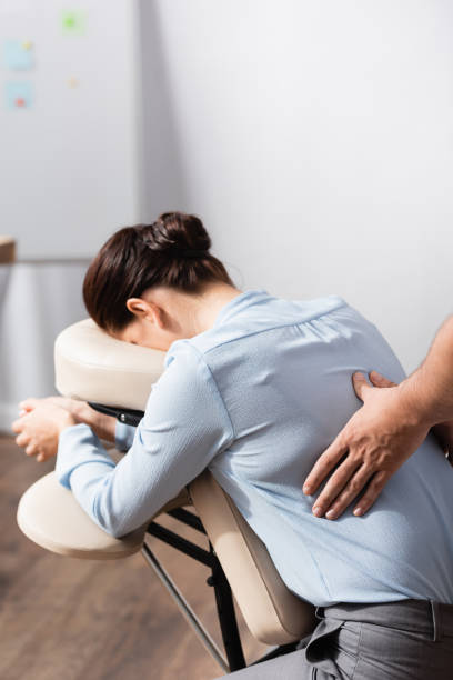 istock Masseur doing seated massage of back for female client on blurred background 1287490051