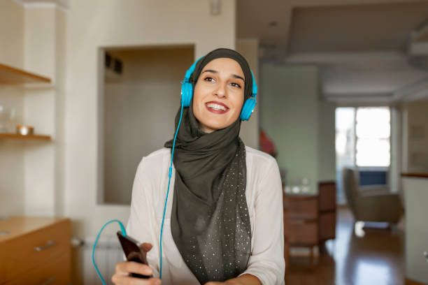 verticale de jeune belle femme musulmane utilisant la musique d’écoute de hijab avec un casque - audio branding photos et images de collection