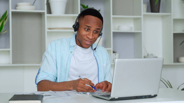 istock Focused black consultant with a headset looks at a laptop 1287491201