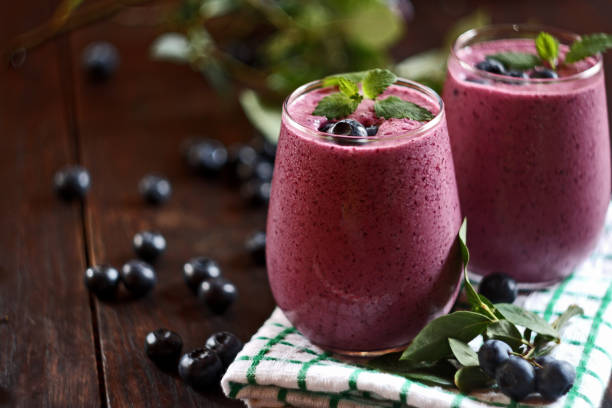 zwei gläser heidelbeer-smoothie auf holzhintergrund. selektiver fokus - smoothie stock-fotos und bilder