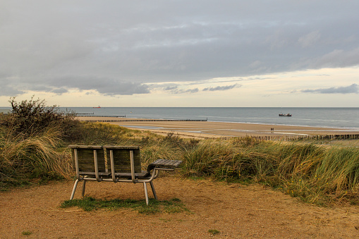 Breskens, Holland - nov 22, 2020: a bench at the dunes at the dutch coast with a beautiful view at the beach and the sea in winter