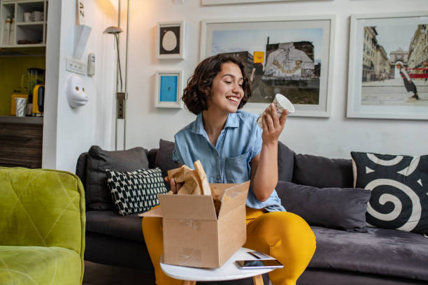 wanita muda membongkar paket yang dia pesan secara online - home delivery potret stok, foto, & gambar bebas royalti