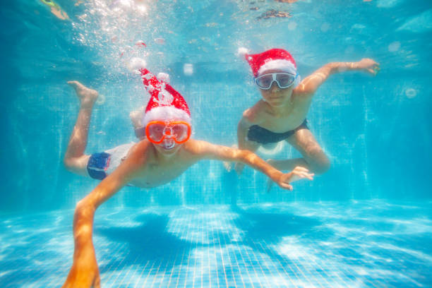 istock Two boys dive in pool on vacation wear Sant hats 1287494060