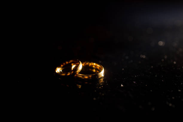 istock Two golden wedding rings on black background. 1287494895