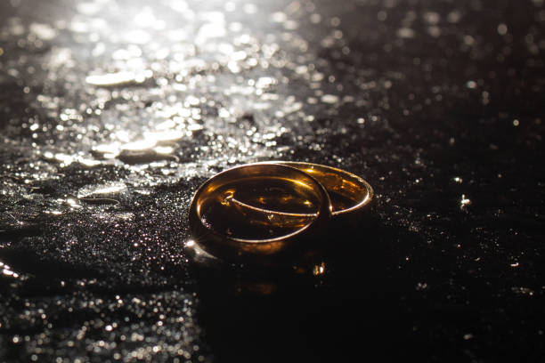 istock Two golden wedding rings on black background. 1287494938