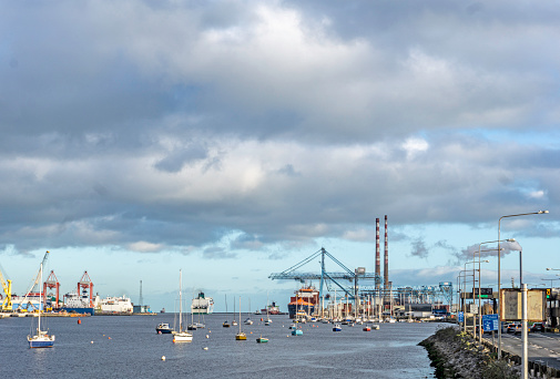 A view of Dublin Port, Ireland,  with a gantry crane in operation, a passenger ferry departing, small boats and the East Link Ferry Bridge.